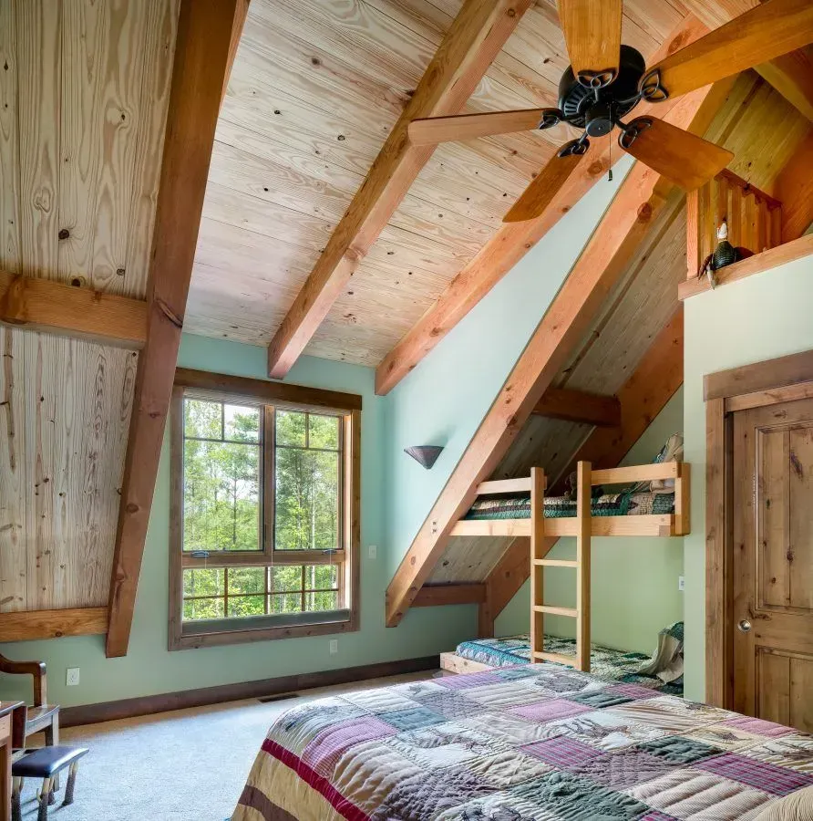 Bedroom with wood beams, bunk beds, and a patterned quilt on the bed.