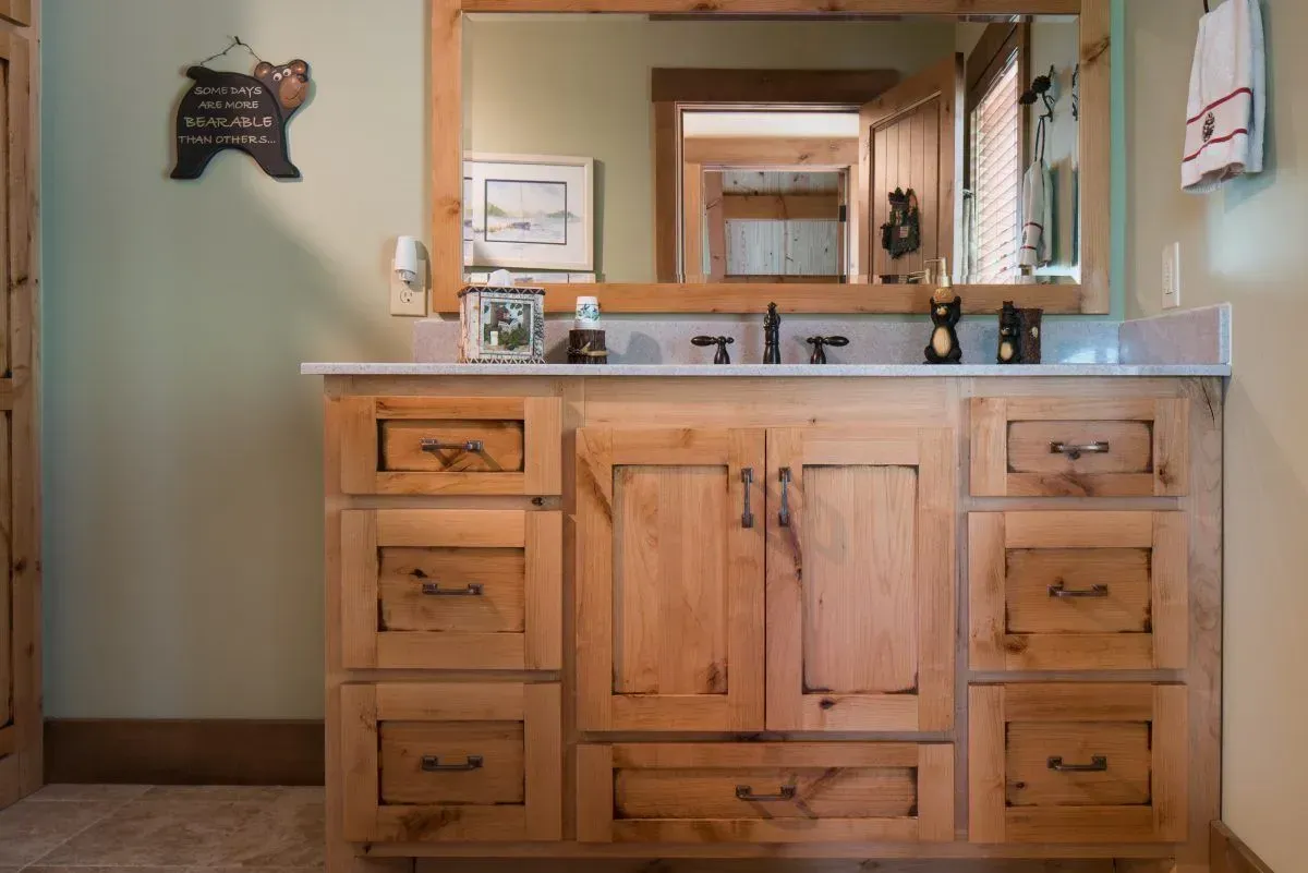 Rustic wooden bathroom vanity with mirror, light countertop, and bear decor.