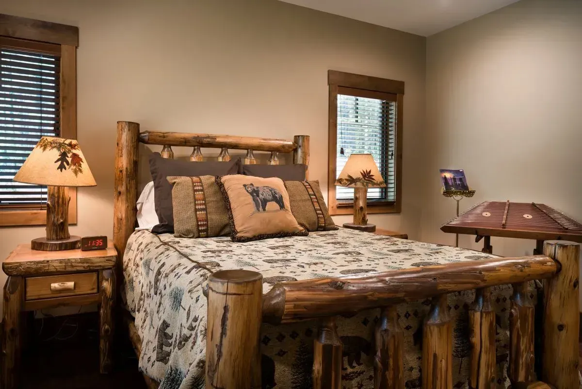 Rustic bedroom with log furniture, floral bedding, and bear-themed pillows.