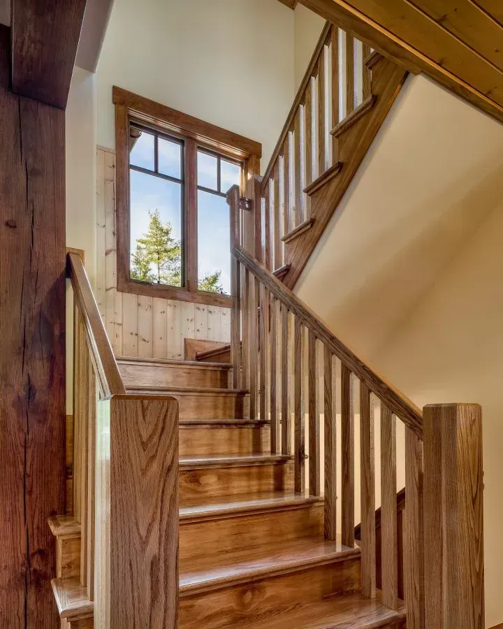 Wooden staircase with railing and window, leading upward.