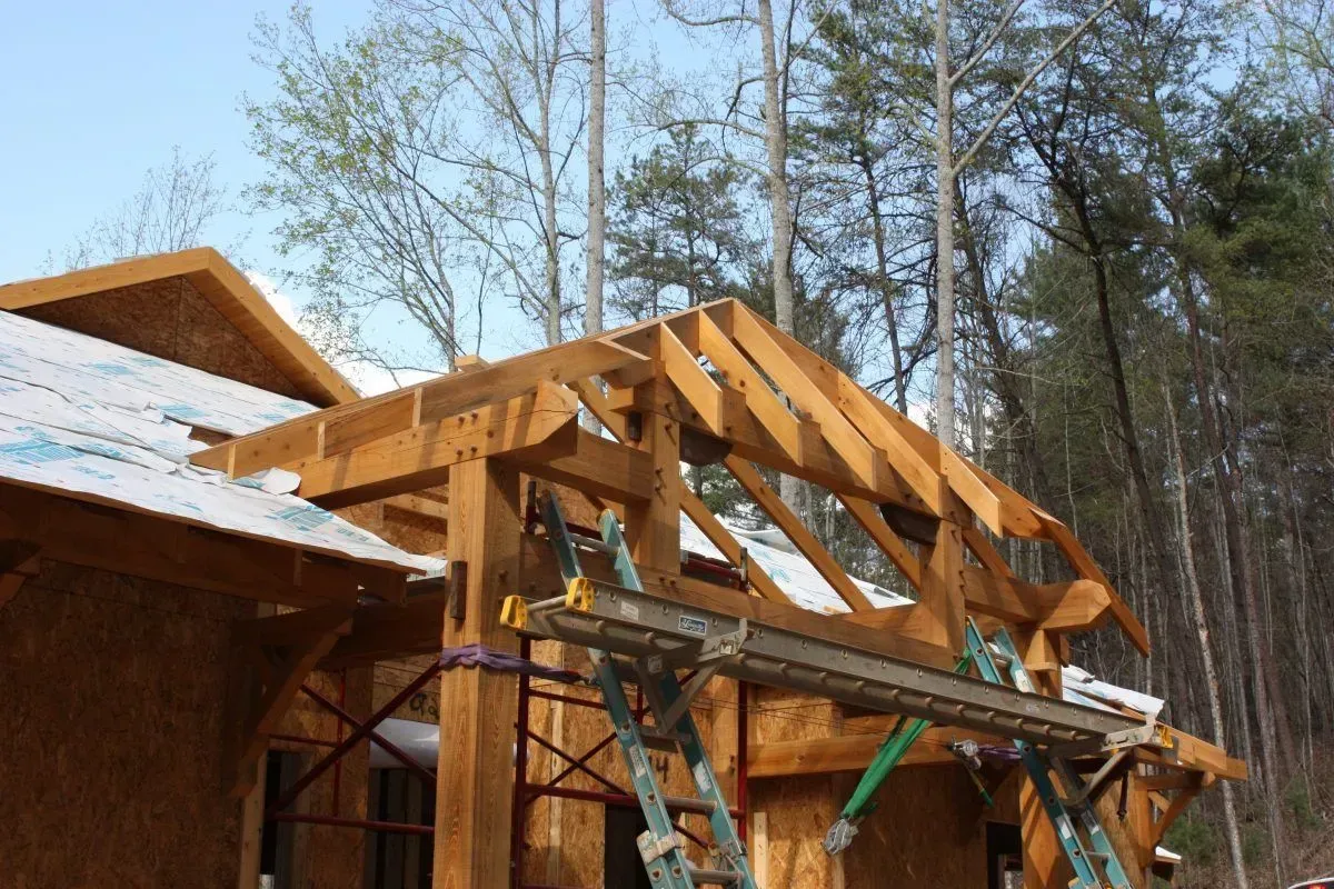 Wooden roof framing under construction outdoors, scaffolding present.