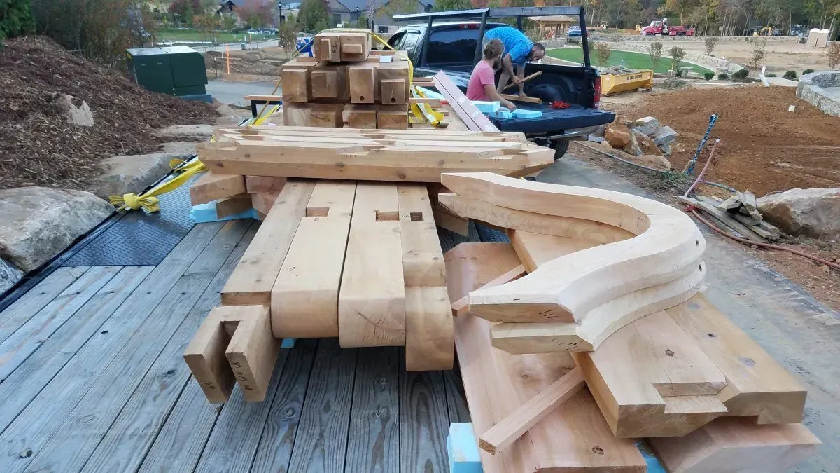 Wooden beams and decorative elements stacked on a trailer at a construction site.