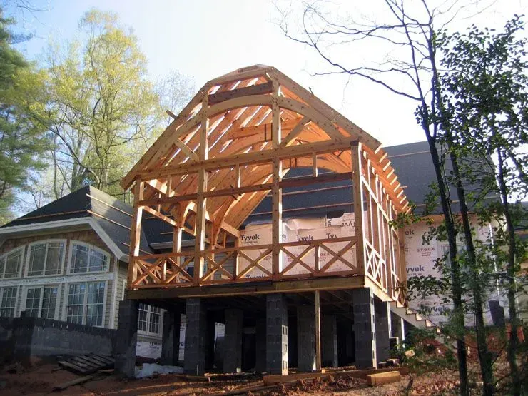 Construction of a wooden porch addition to a house, supported by dark pillars.