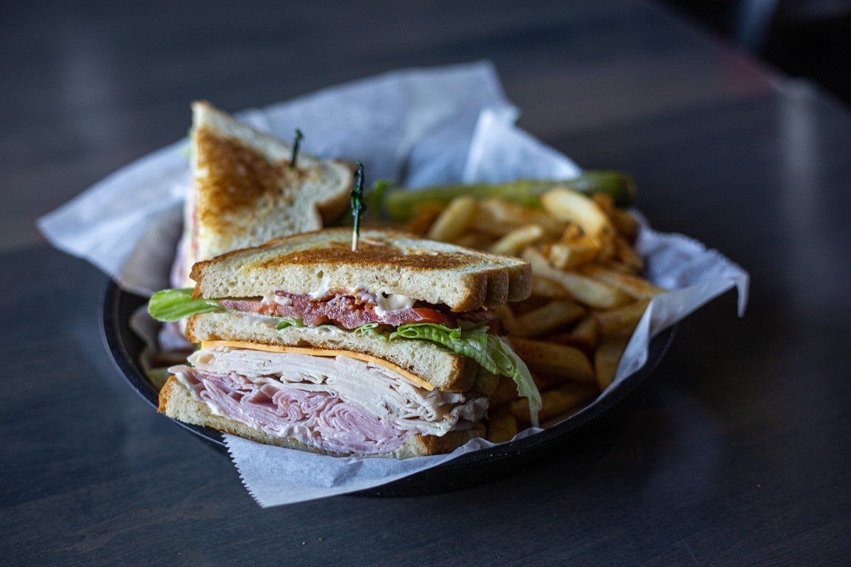 A sandwich and french fries in a basket on a table.