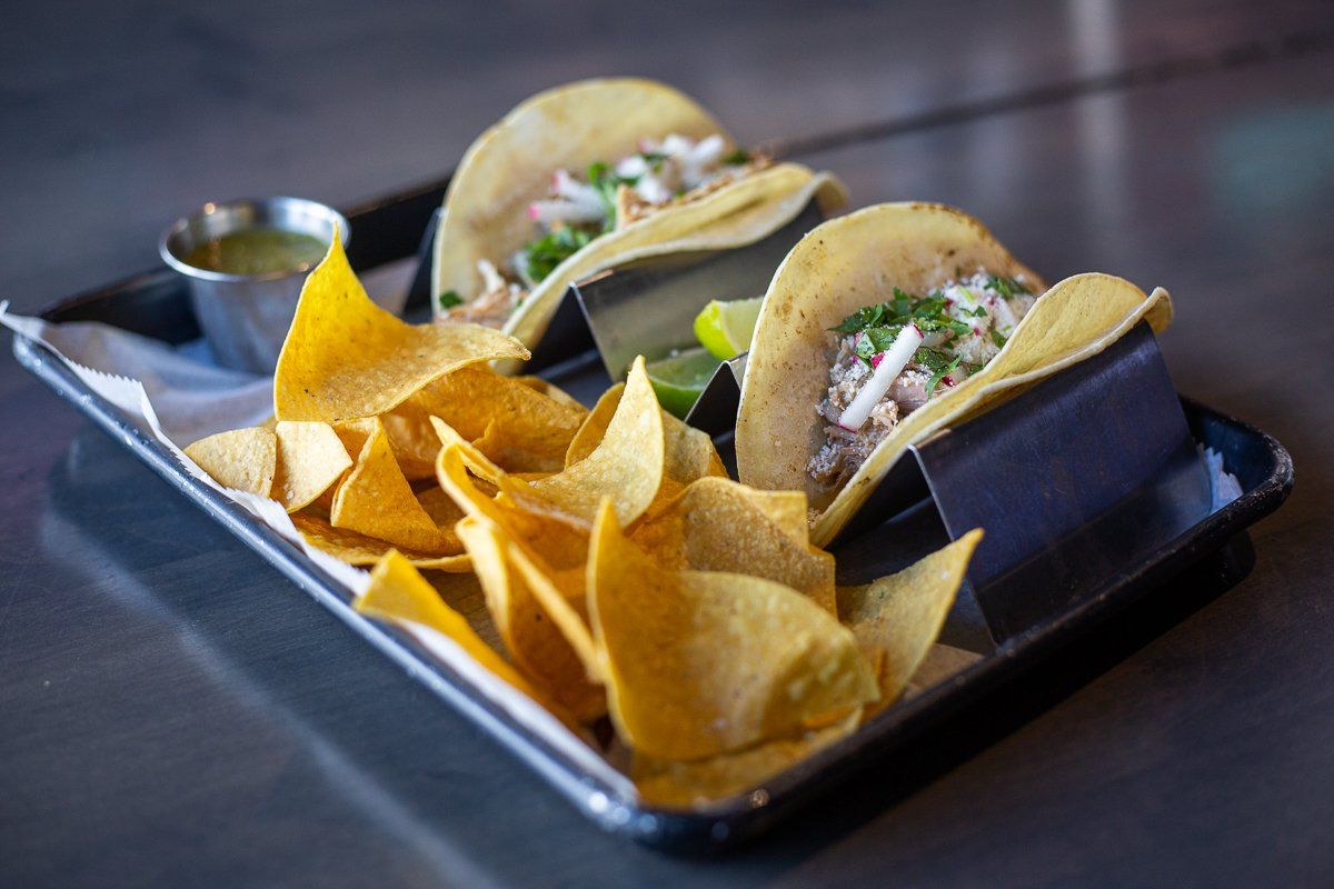 A tray of tacos and tortilla chips on a table.