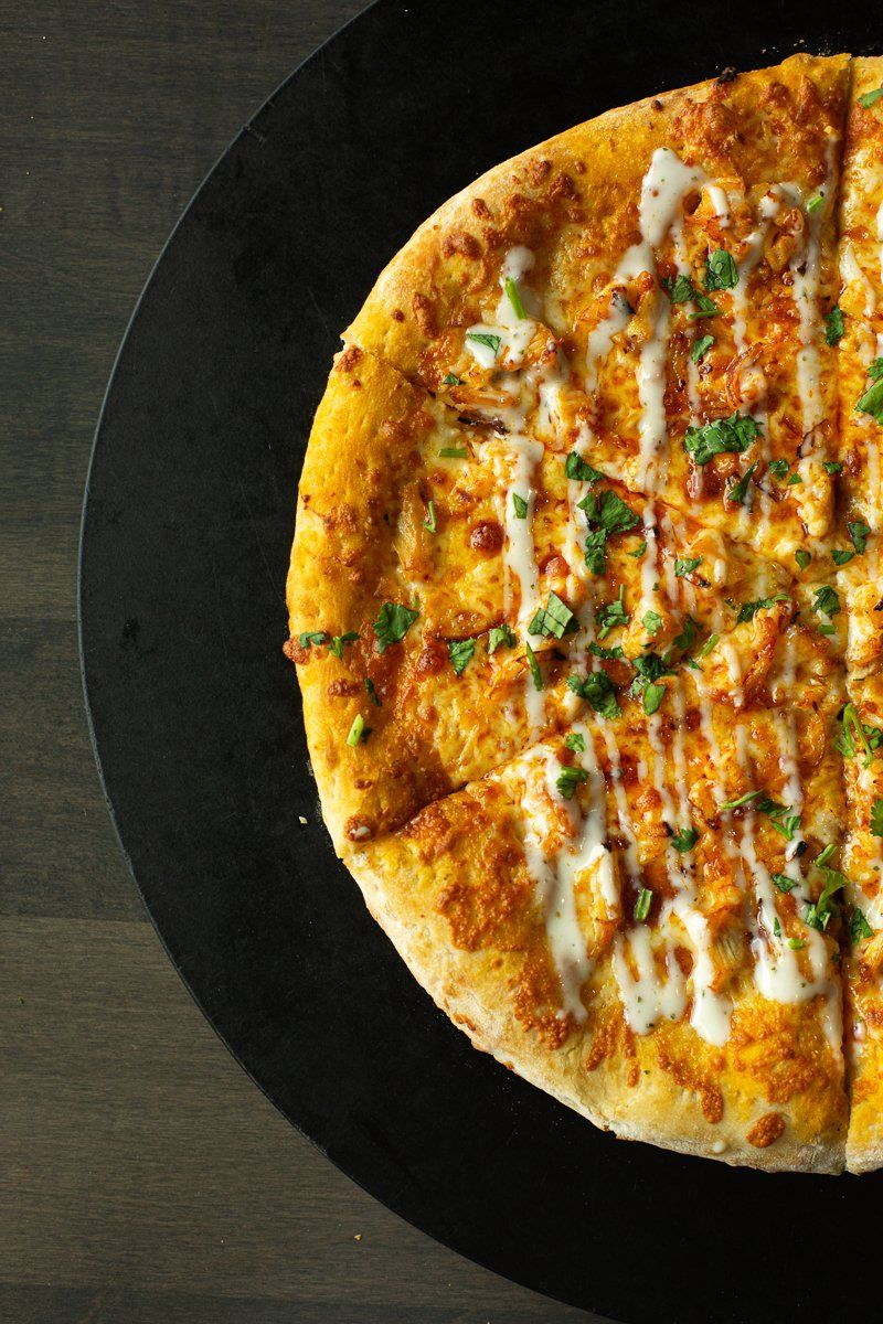 A pizza is sitting on a black plate on a table.