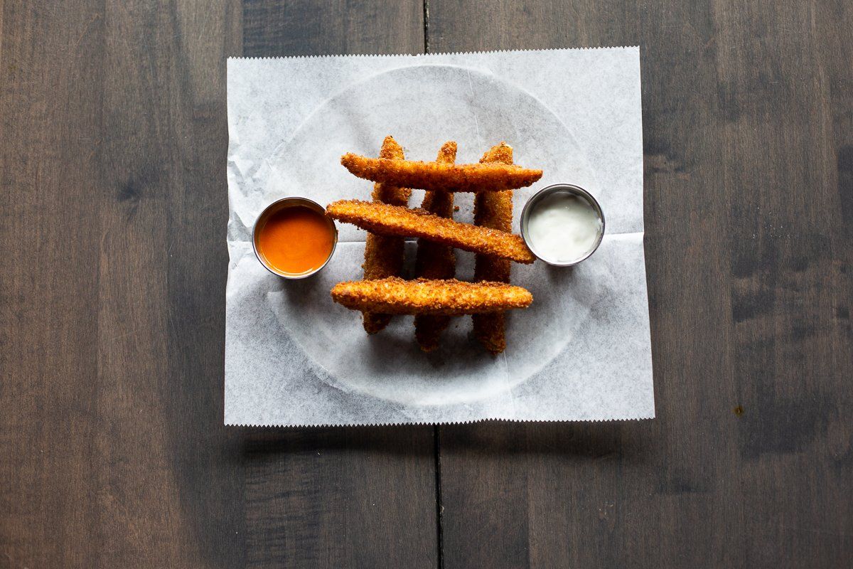 A plate of chicken fingers with dipping sauce on a wooden table.