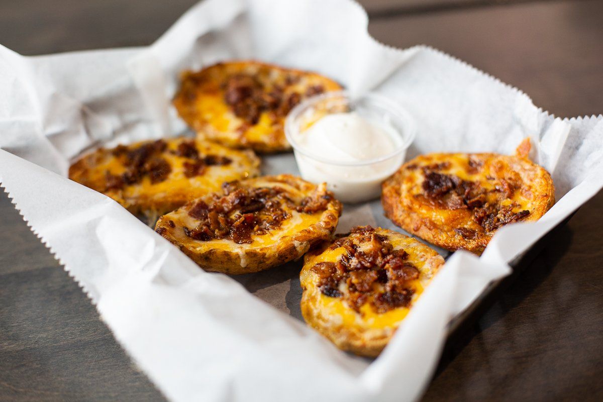 A basket of potato skins with bacon and cheese on a table.