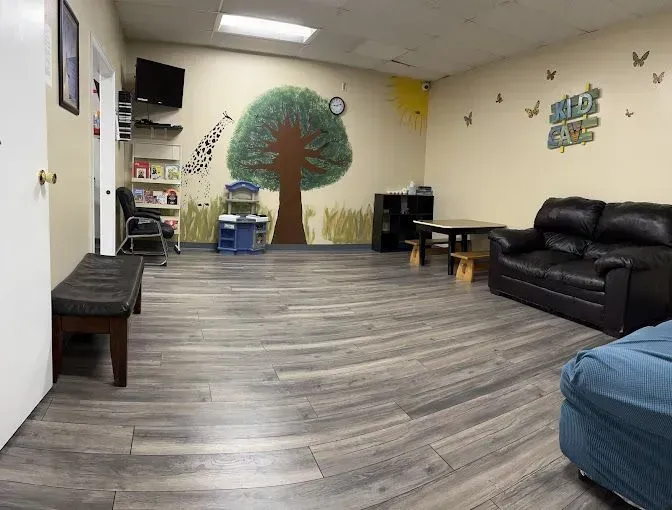 Interior of a room with painted tree mural, play area, sofa, and bench.