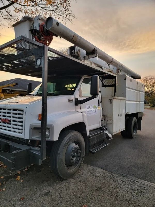 White GMC utility truck with a crane in a residential setting under an evening sky.