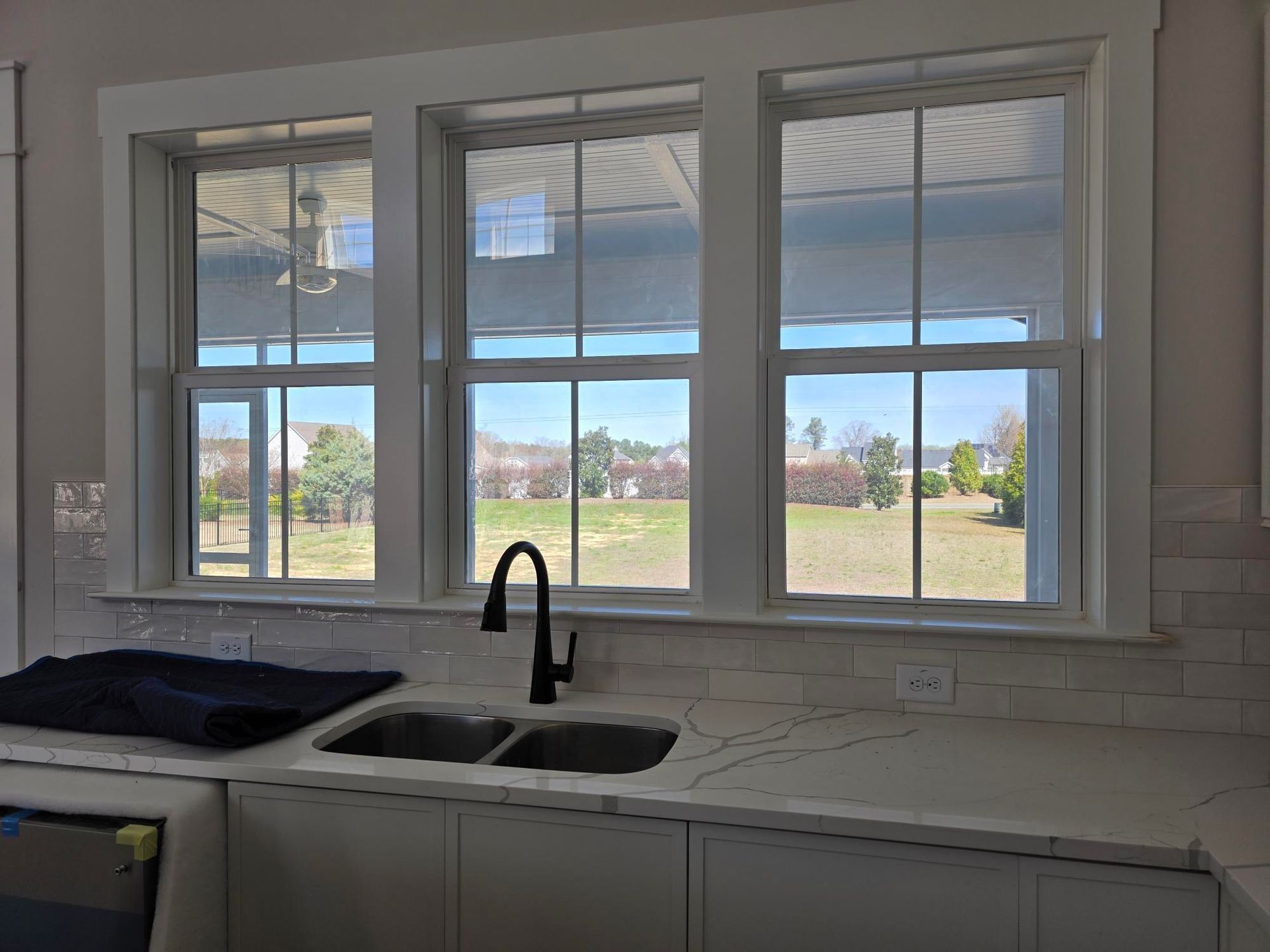 Kitchen sink and window view of a grassy field through white-framed panes