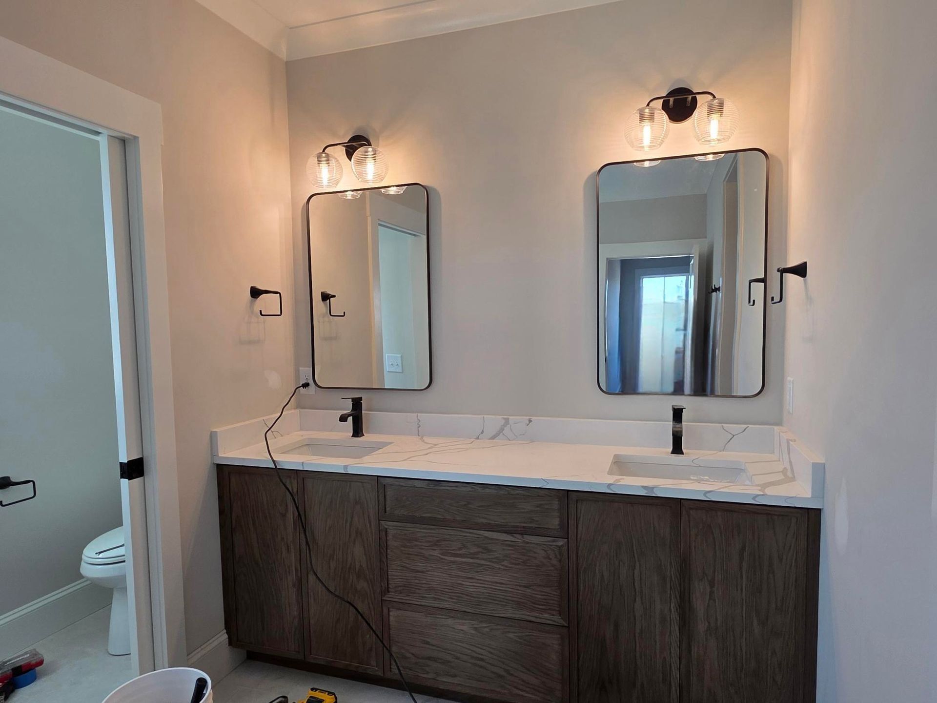 Modern bathroom vanity with double mirrors, wall sconces, and dark wood cabinets