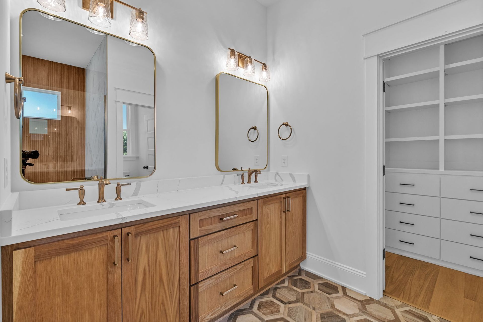 Spacious white bathroom with double vanity, wood cabinets, mirrors, and open shelving closet.