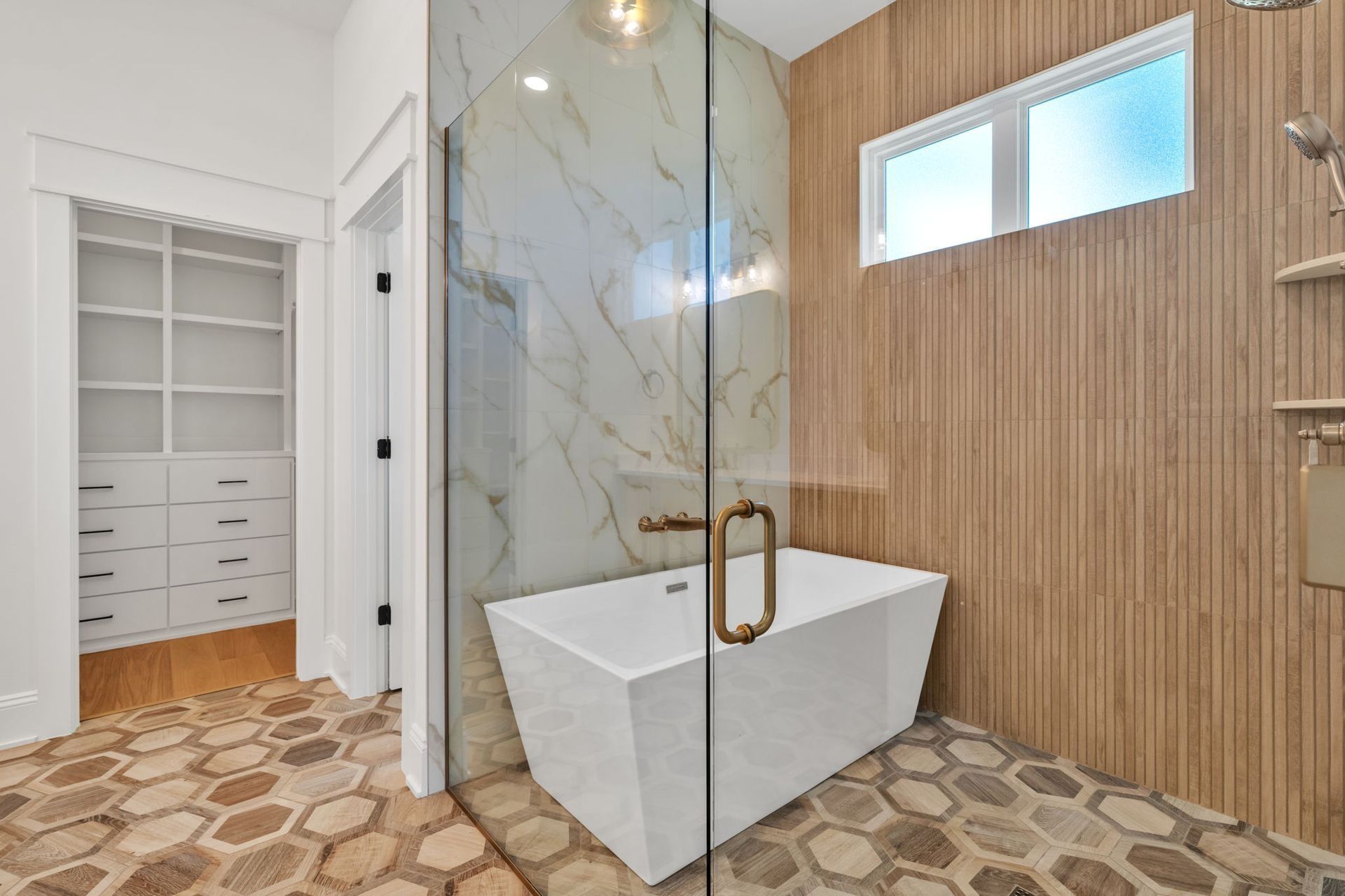 Modern bathroom with glass shower, freestanding tub, wood paneling, and patterned tile floor