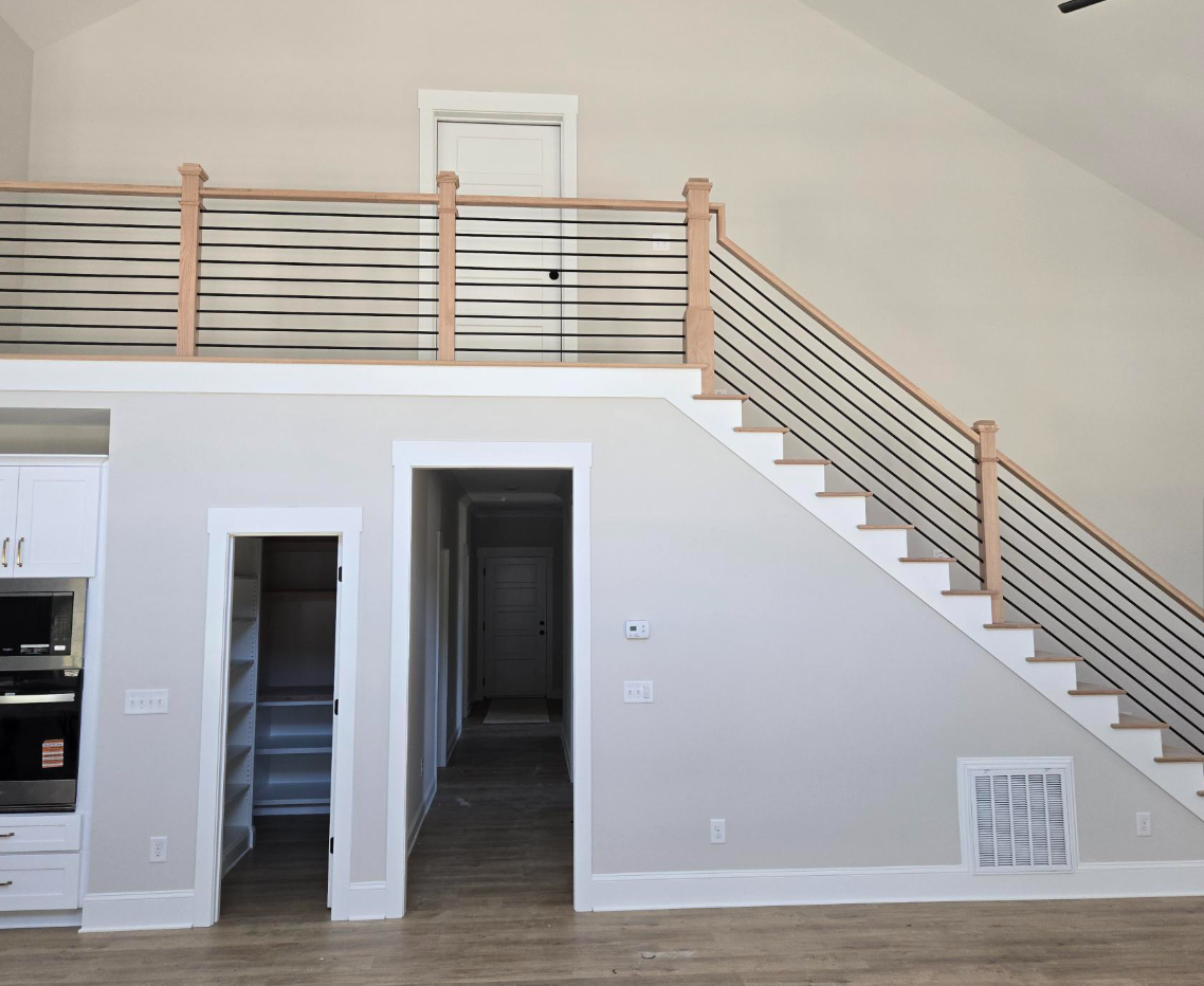 Modern interior with a loft staircase, white walls, wood railing, and hardwood floor