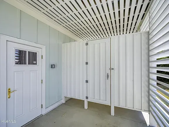Covered porch with two white doors, slatted ceiling, and pale blue siding