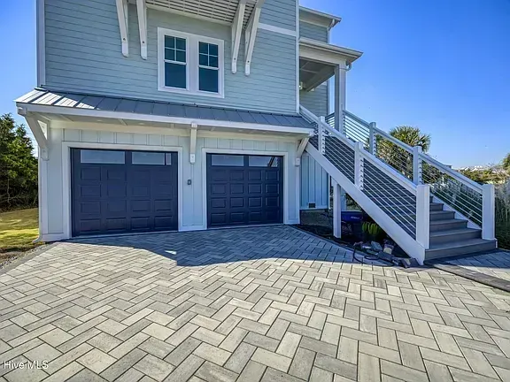 Gray house with double garage and white staircase beside a paved driveway