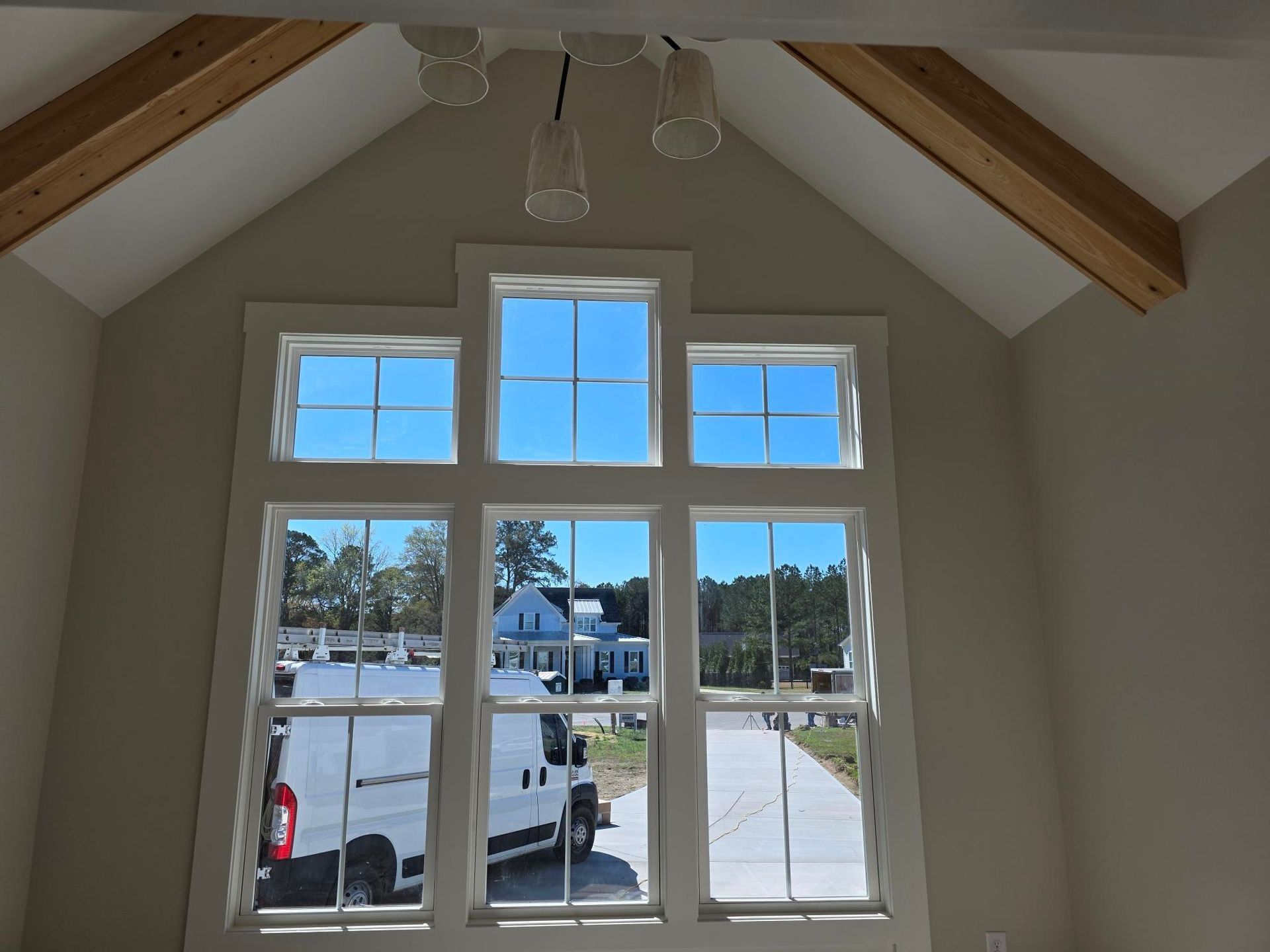 Bright window wall with white trim and wood-beamed ceiling, looking out onto a sunny street.