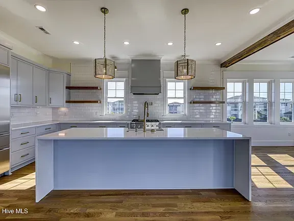Bright modern kitchen with gray cabinets, large island, pendant lights, and white countertops