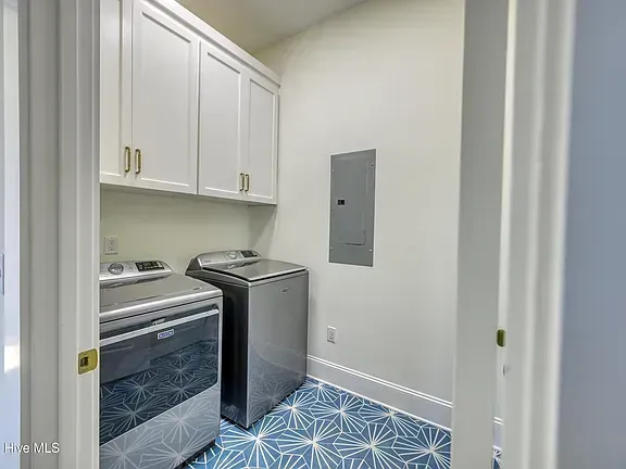 Laundry room with white cabinets, washer, dryer, and blue patterned tile floor