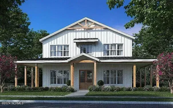 Front view of a white farmhouse with a covered porch, centered under a blue sky with trees around it
