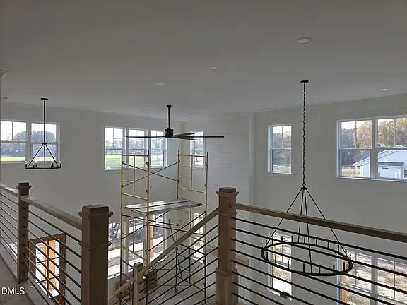 Open loft interior with white walls, large windows, ceiling fans, and metal railings overlooking below.