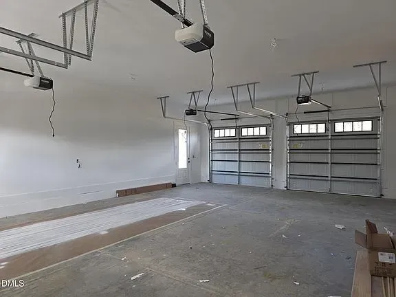 Empty two-car garage with white walls, concrete floor, and open overhead door rails.