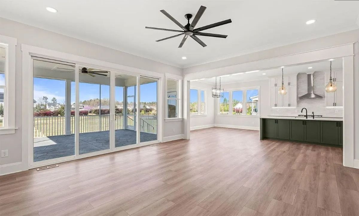 Bright open living room with large windows, wood floors, and a modern black ceiling fan