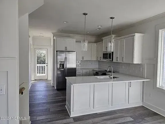 Bright modern kitchen with white cabinets, stainless steel appliances, and gray flooring