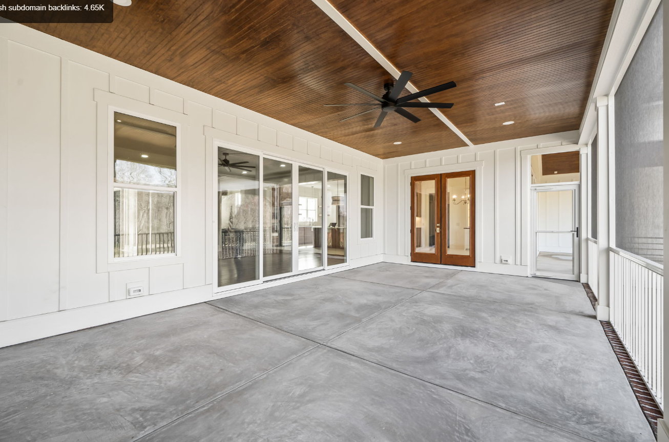 Spacious covered patio with concrete floor, wood ceiling, ceiling fan, and glass doors to the house