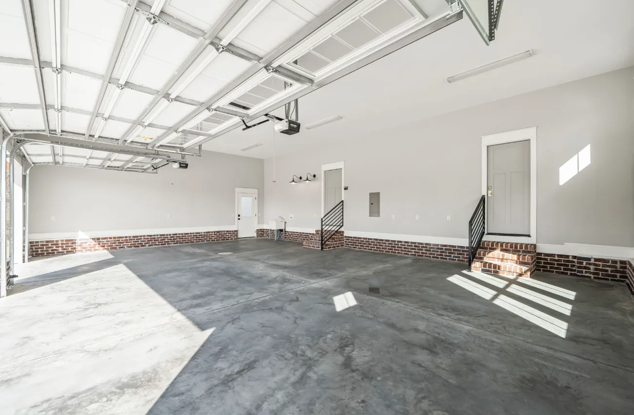 Empty unfinished garage interior with exposed ceiling, concrete floor, and white walls
