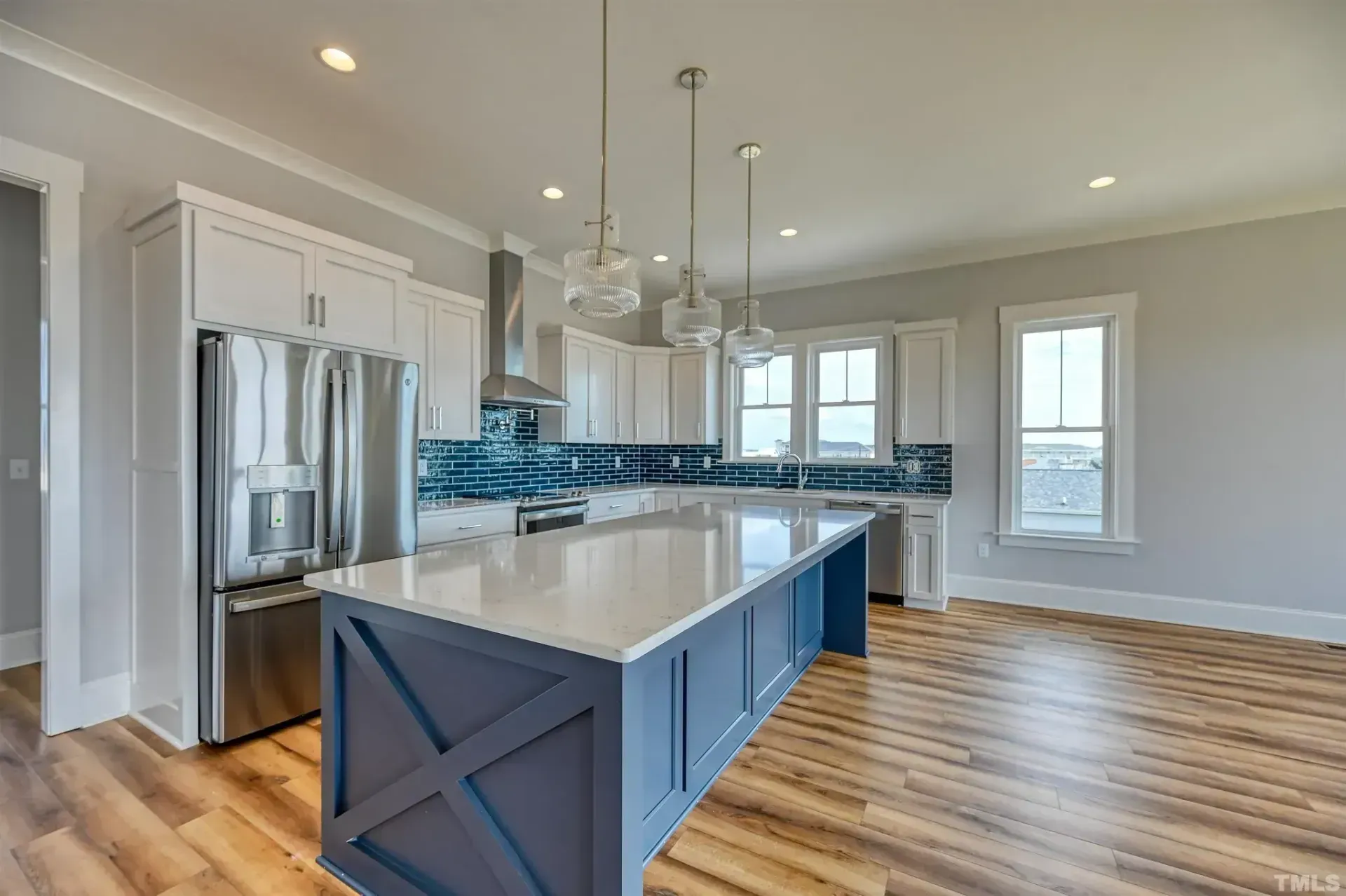 Modern kitchen with white cabinets, stainless steel appliances, blue island, and wood flooring