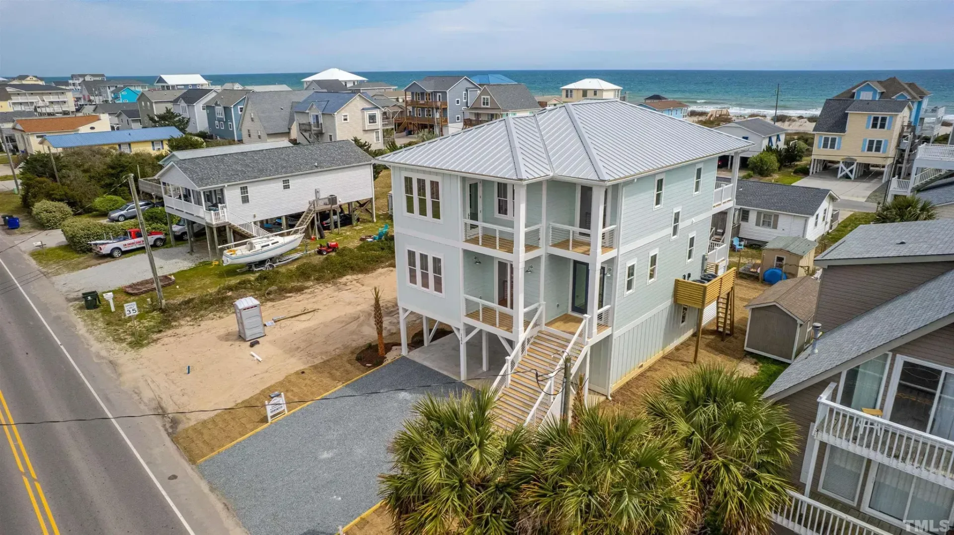 Coastal neighborhood with a white stilt house near the beach and ocean in the background