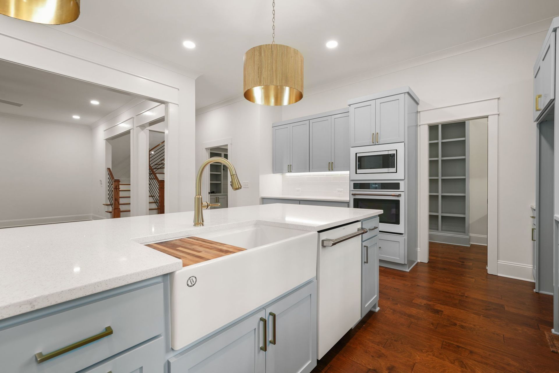 Bright white modern kitchen with island, gold pendant lights, and hardwood floors