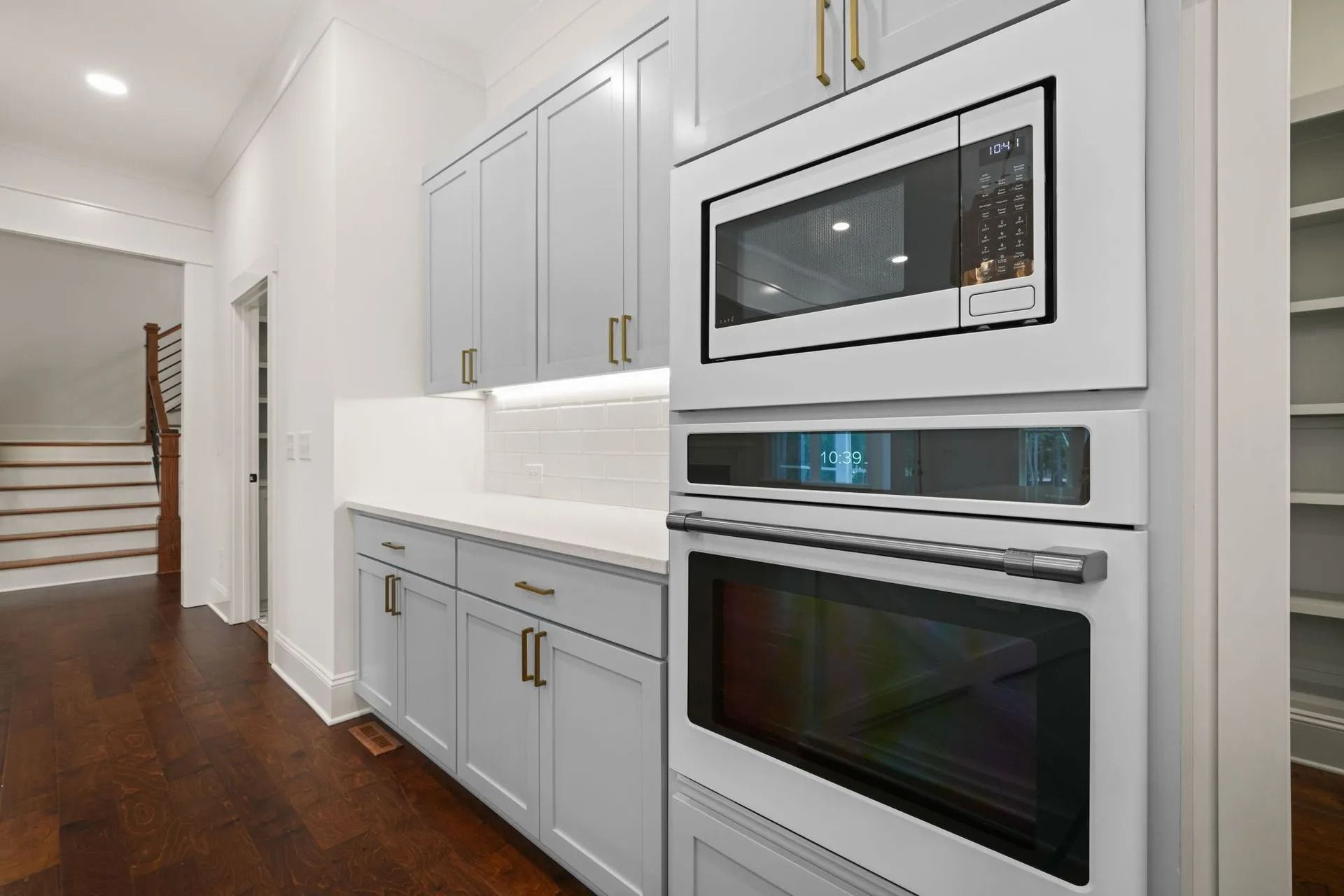 Modern kitchen with gray cabinets, white countertops, and built-in microwave and oven.