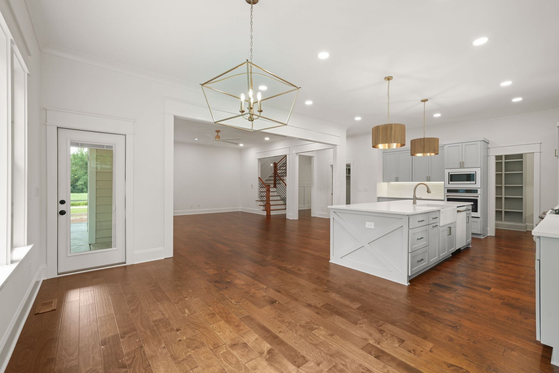 Spacious modern kitchen and living area with white cabinets, hardwood floors, and a central island.