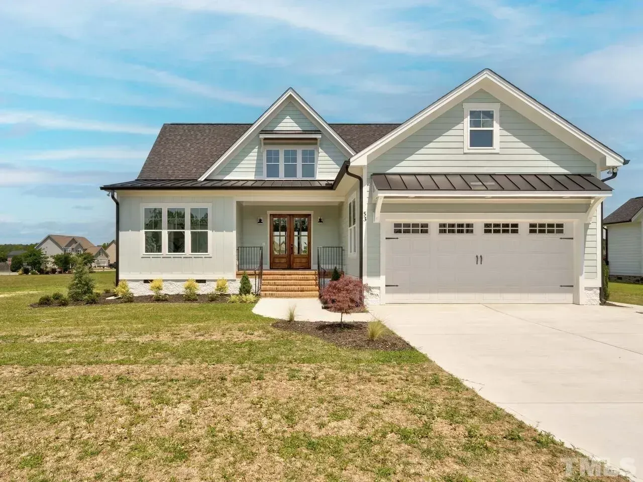 Suburban house with gray siding, front porch, attached garage, and a concrete driveway.