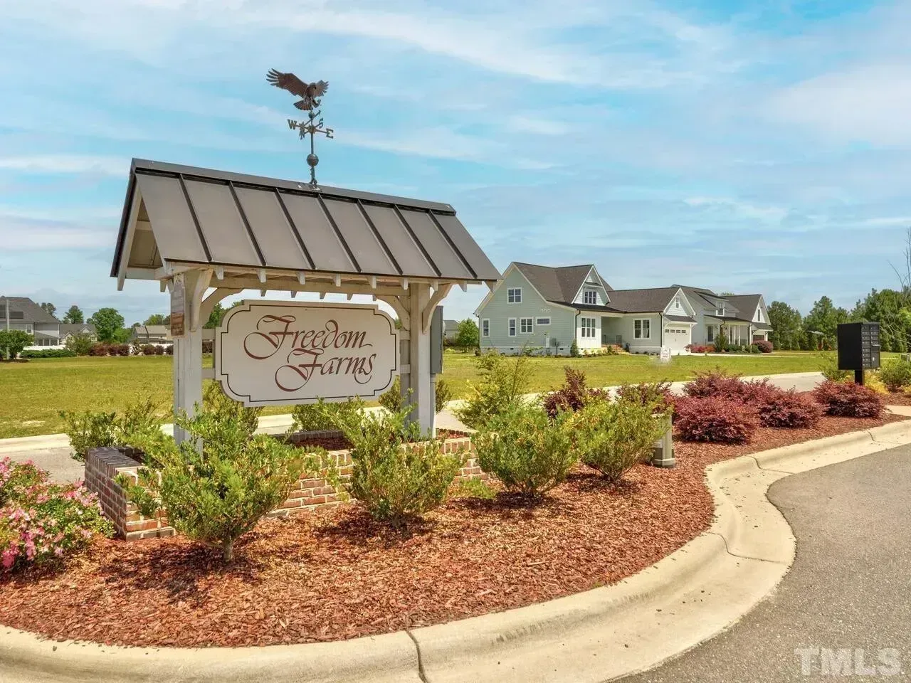 Subdivision entrance sign with landscaped flower beds and homes in the background