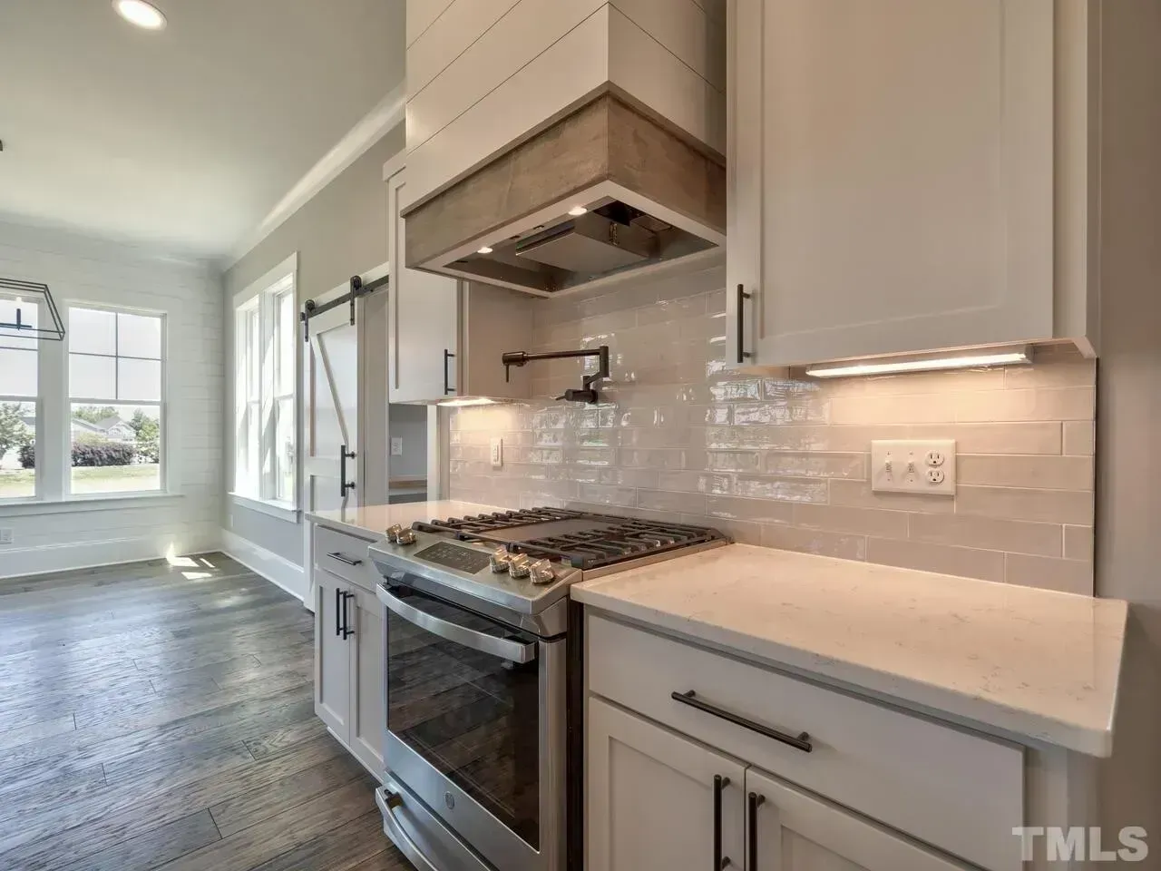 Bright modern kitchen with white cabinets, stainless range, and glossy subway tile backsplash