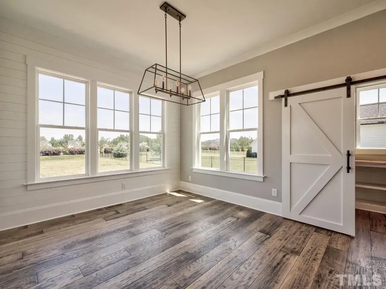 Bright empty room with large windows, wood floor, and a barn-style sliding door