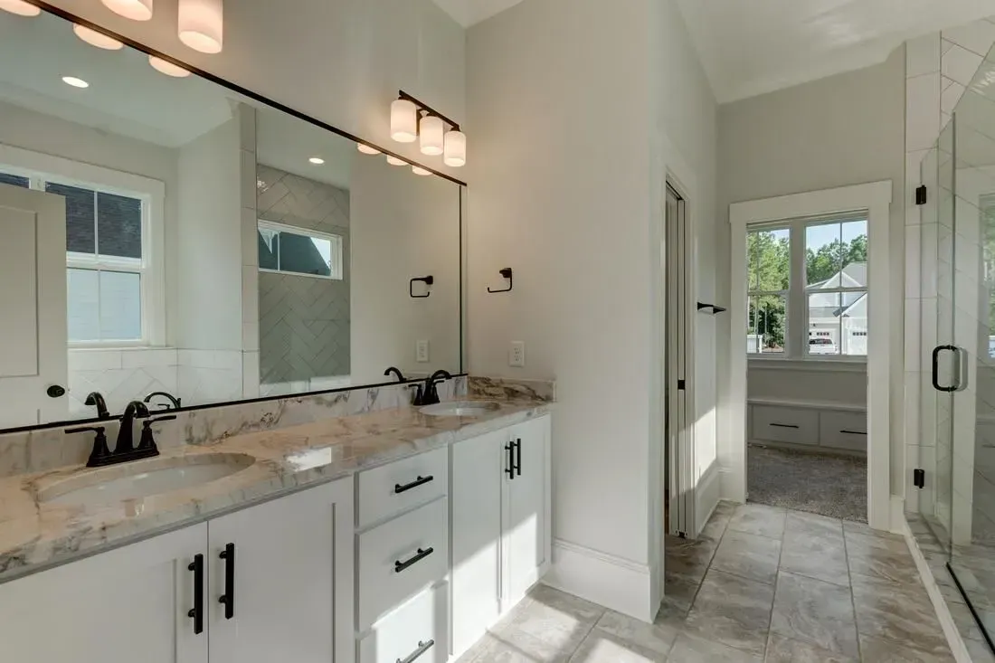 Bright, modern bathroom with a white double vanity, large mirror, and glass-enclosed shower.