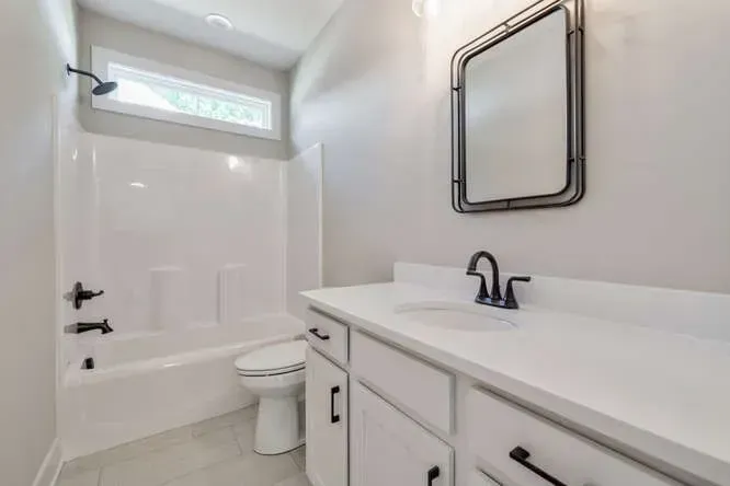 Modern bathroom featuring a white vanity with black hardware, a rectangular wall mirror, and a tub-shower combination.