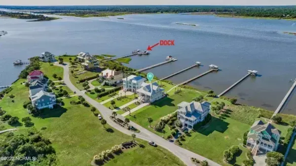 An aerial view of waterfront houses with private docks extending into a river. One dock is labeled