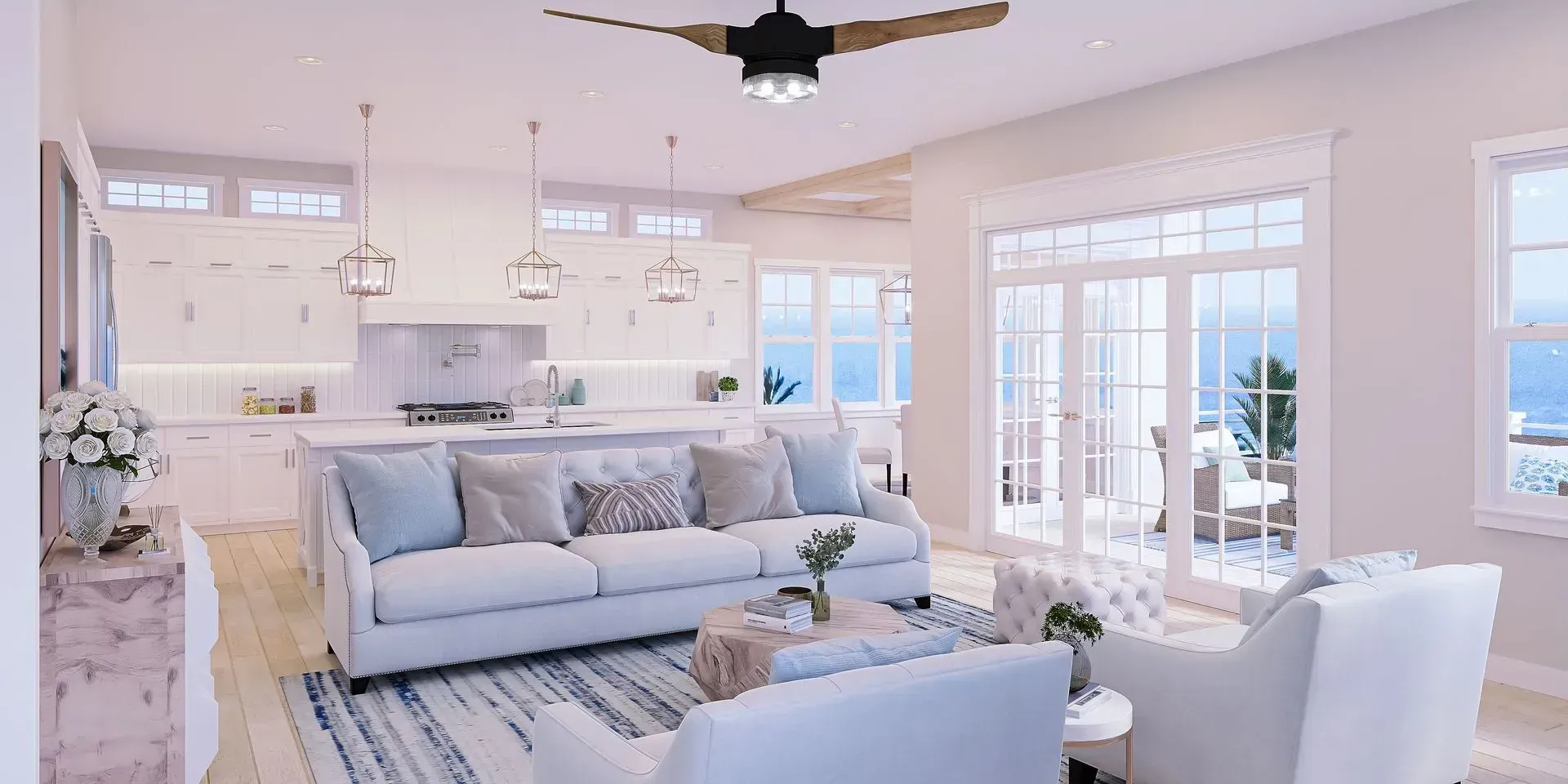 A bright, open-concept coastal home interior with a white kitchen, sofa, armchairs, and floor-to-ceiling glass doors.