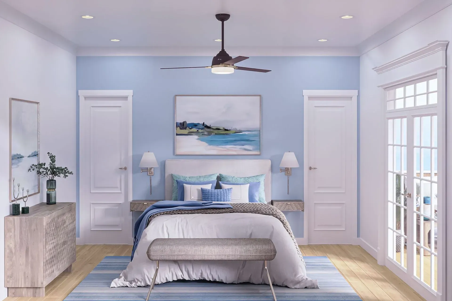 A bedroom featuring a bed with blue accents, light walls, wooden furniture, and a ceiling fan under soft lighting.