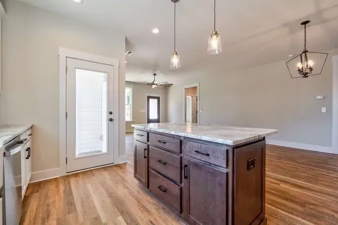 A modern kitchen island with dark wood cabinets and a marble countertop, situated in a home interior with light floors.