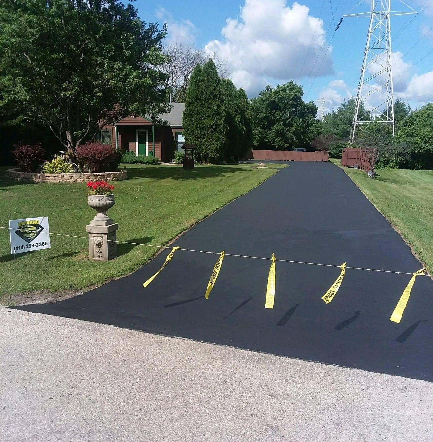 A sign is sitting on the side of an asphalt driveway.