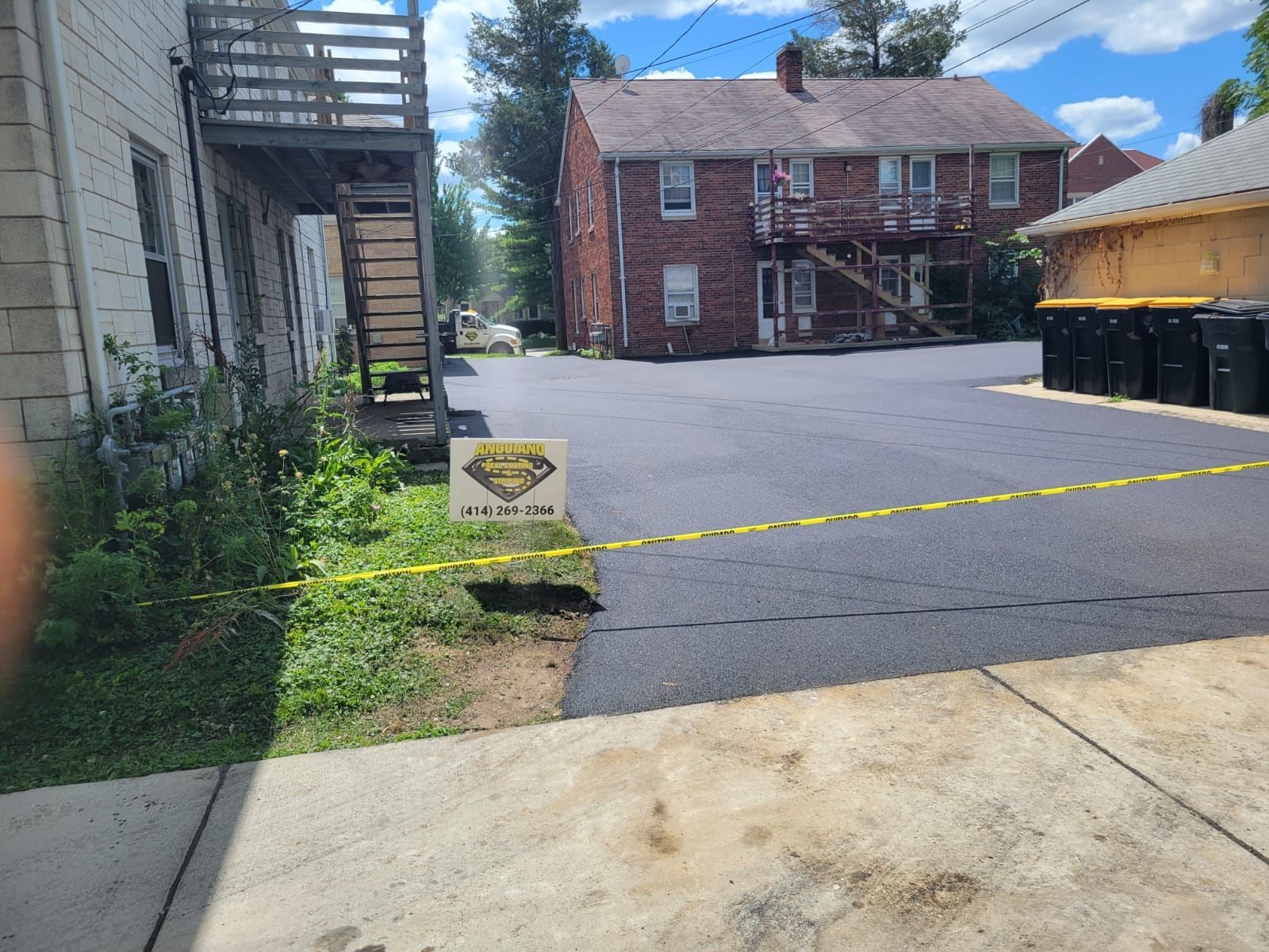 A brick building with stairs and an asphalt driveway in front of it.