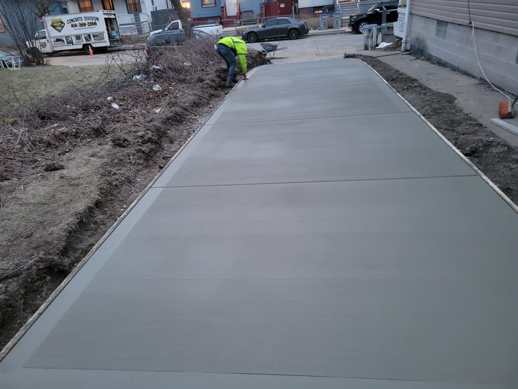 A man is laying concrete on a sidewalk in front of a house.