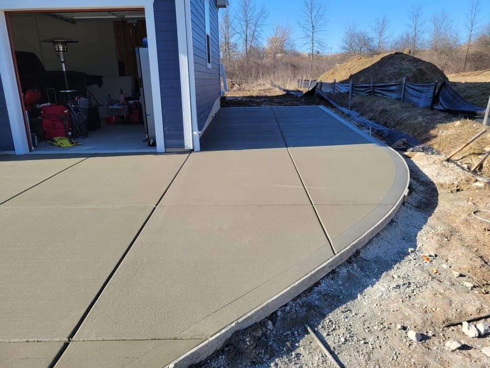A concrete driveway is being built in front of a garage.